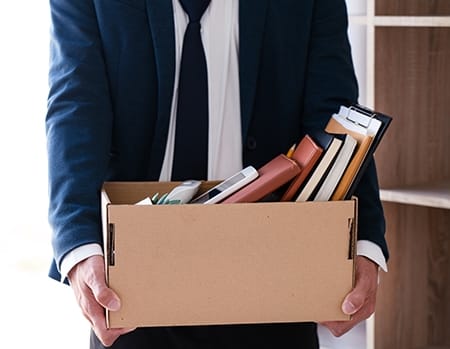 An employee has been fired by wrongful termination and collects his belongings in a box.