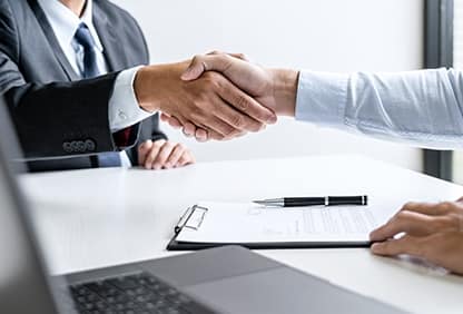 An employer and worker shake hands after signing an employment contract.